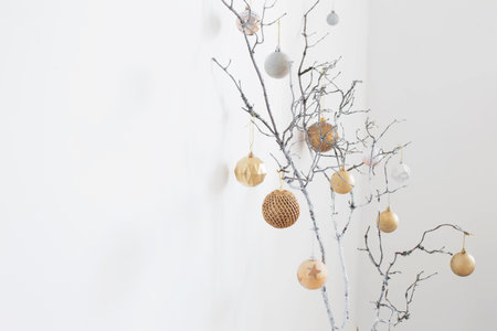 christmas branches with golden and white balls on white wall background