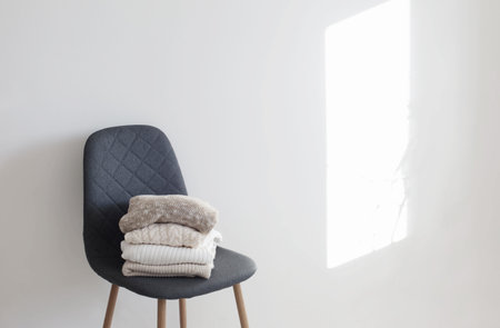 stack of sweaters on gray modern chair in white room