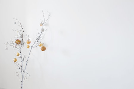 christmas branches with golden and white balls on white wall background