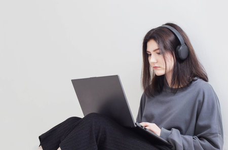 teenager girl with laptop sitting on floor in white room