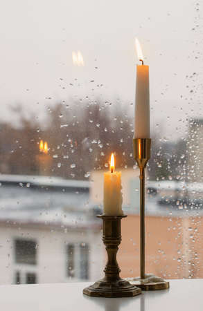 burning candles on background rainy window paneの写真素材