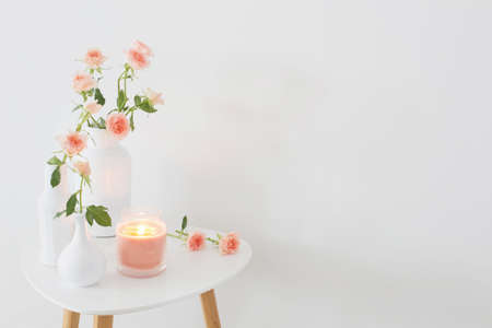 pink roses in white vase on table on background white wallの写真素材