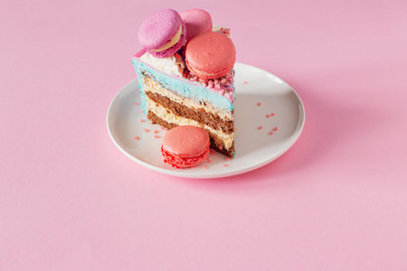 piece of cake with pink and blue decor on white plate on pink background