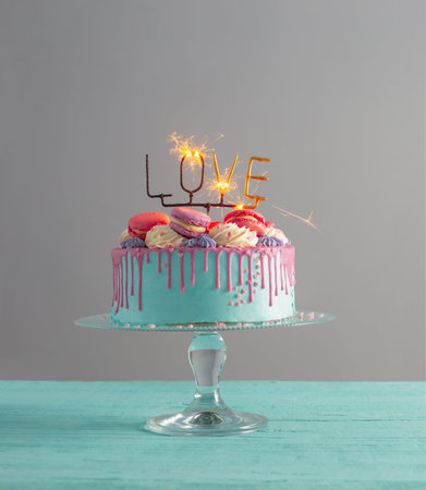 cake with pink and blue decor and burning sparkler with text love