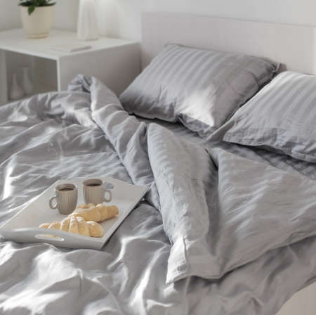 two croissants and two cups of coffee on bedの写真素材