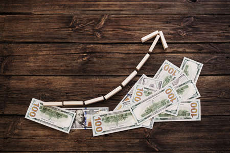 dollars with wooden arrow on dark wooden background, dollar growth conceptの写真素材