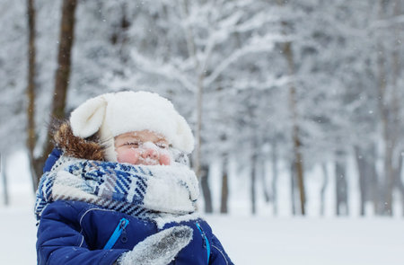 funny little happy boy in snowy winter parkの写真素材