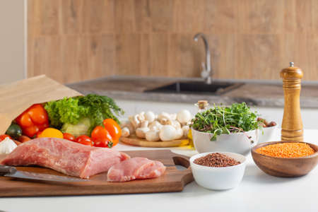 raw meat and vegetables on the table in the kitchenの写真素材