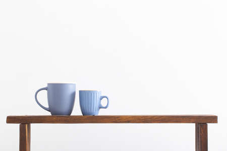 two blue cups on wooden shelf on white backgroundの写真素材