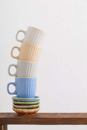 colorful cups on wooden shelf on white backgroundの写真素材