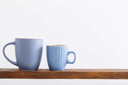 two blue cups on wooden shelf on white backgroundの写真素材