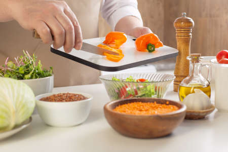 man preparing healthy vegetarian food on table in kitchenの写真素材