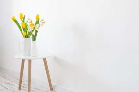 white and yellow spring flowers in vase on white backgroundの写真素材