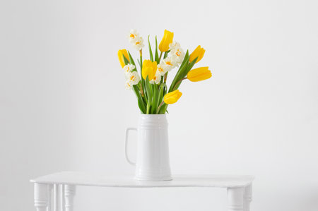 white and yellow spring flowers in vase on white backgroundの写真素材