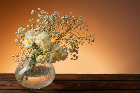 white flowers in glass vase on wooden tableの写真素材
