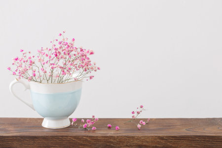 pink flowers in cup on white background
