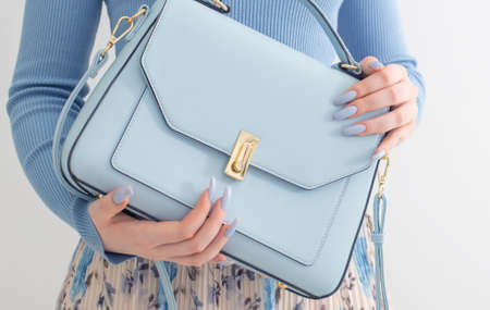 young girl in blue blouse and pleated skirt with blue handbag on white backgroundの写真素材