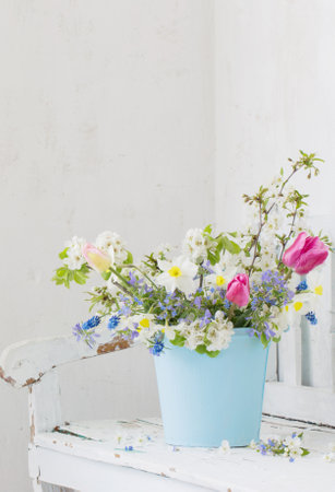 spring flowers in vintage white interior with old wooden benchの写真素材