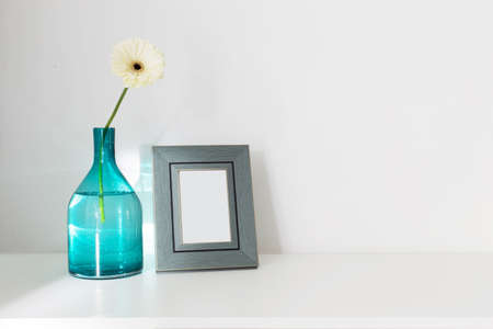 gerber in glass vase and wooden frame on white wooden wallの写真素材