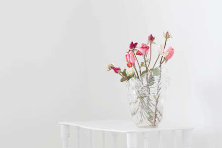 pink and white roses on glass vase on white wooden shelfの写真素材