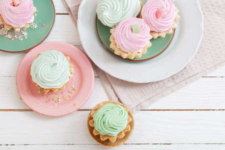 cupcakes on plates on white wooden backgroundの写真素材