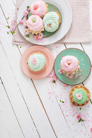 pink and green cupcakes with spring flowers on white wooden backgroundの写真素材