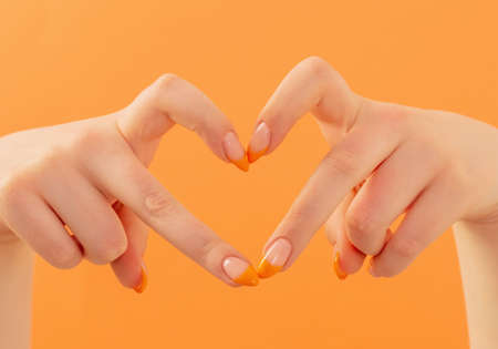 female hand with manicure on orange backgroundの写真素材