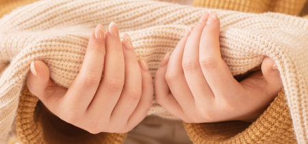 woman's hands with manicure with knitted blanket