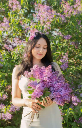 young girl with blooming lilac in sunlightの写真素材