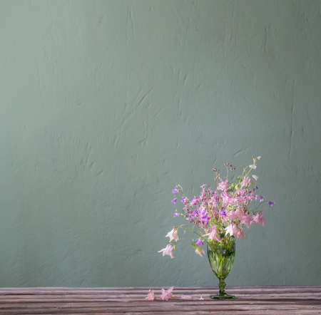 wild flowers in green glass on background green wallの写真素材