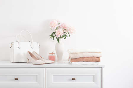 white dresser with clothes and flowers in white roomの写真素材