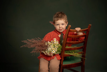 vintage portrait of little boy with wild flowers on green backgroundの写真素材