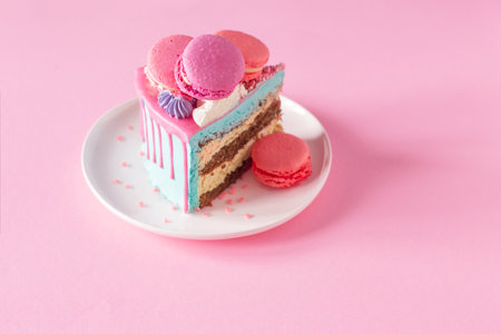 piece of cake with pink and blue decor on white plate on pink backgroundの写真素材