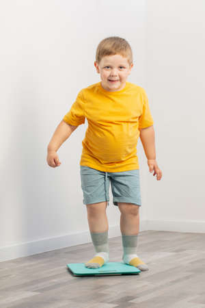 overweight little boy on scales at homeの写真素材