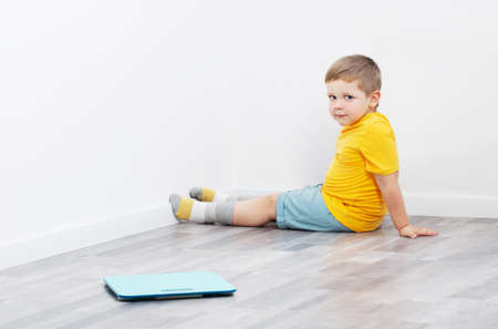 overweight little boy on scales at homeの写真素材
