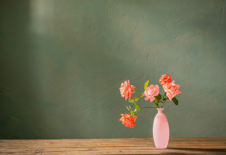 pink roses in glass pink vase on wooden table on background dark wallの写真素材
