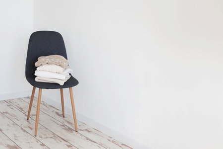stack of sweaters on gray modern chair in white roomの写真素材