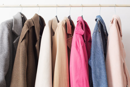 female autumn clothes on hangers in white roomの写真素材