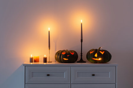 black halloween pumpkin with burning candles in white interiorの写真素材
