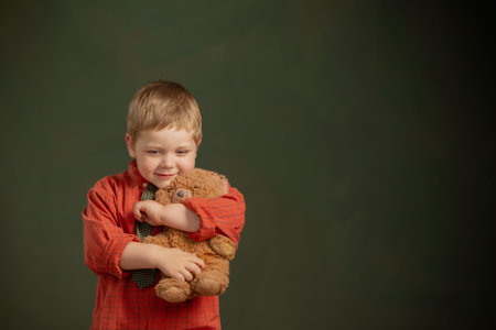 little boy with teddy bear and old suitcase on dark backgroundの写真素材