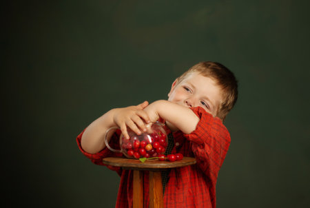 little funny boy with cherry on background dark green wallの写真素材