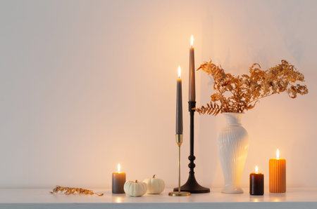 beautiful autumn home decor with burning candles in white interior