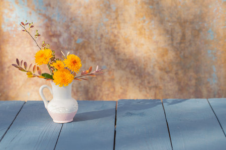 chrysanthemum flowers in jug on background old wall in sunlightの写真素材