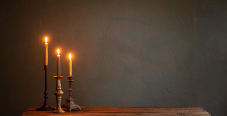 burning candles in vintage candlesticks on dark background