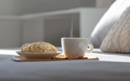 cup of coffee on wooden tray on bed in cozy bedroomの写真素材