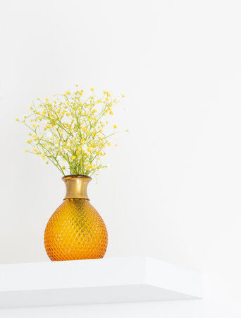 yellow gypsophila in glass vase in white roomの写真素材