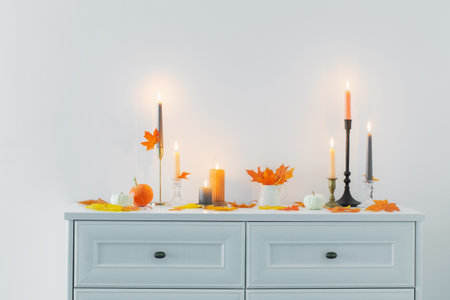 beautiful autumn home decor with burning candles in white interiorの写真素材