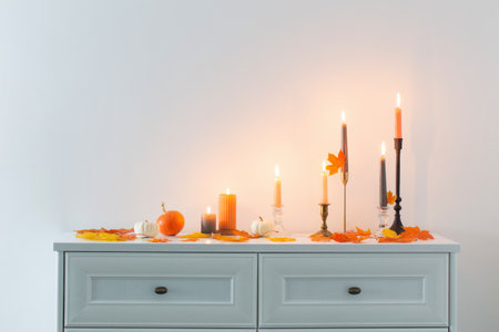 beautiful autumn home decor with burning candles in white interiorの写真素材