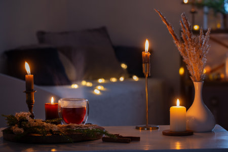 hot tea in thermo glass with christmas decor and burning candles at homeの写真素材