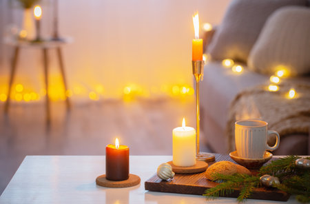 cup of coffee with burning candles and christmas decorations at homeの写真素材